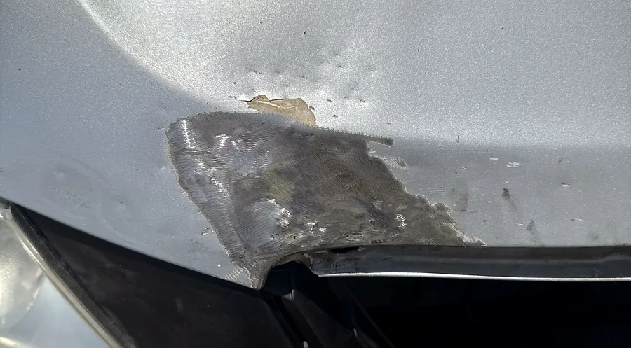 Sanded body filler repair on a front bumper corner beside the headlight during panel work at Sultan Motors