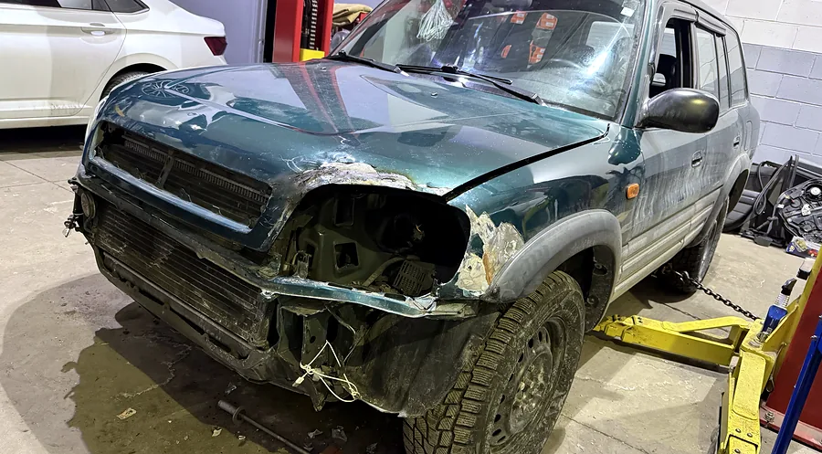 Toyota RAV4 chained to a floor-anchored frame-pulling machine for structural collision repair at Sultan Motors